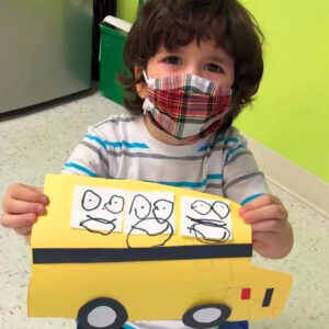 A pre-k boy show off his schoolbus artwork