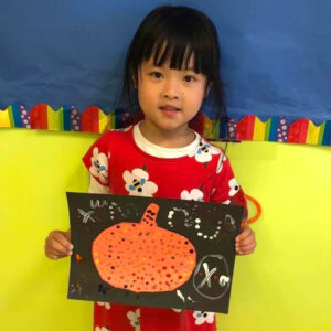 A pre-k girl shows off her halloween themed artwork