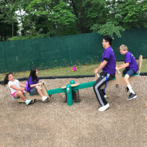 Kids and their teacher play on a see saw