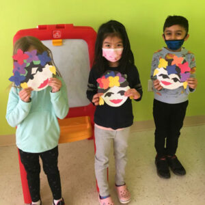 Boys and girls show off artwork they created after school at Kiddosland