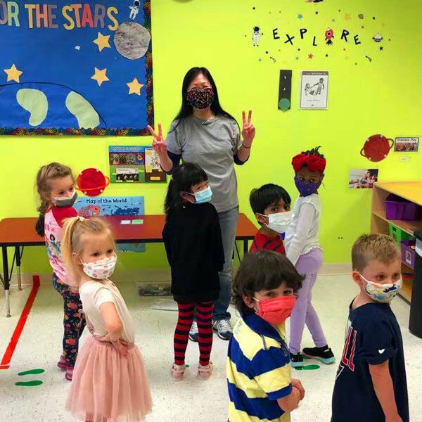 A pre-k teacher and students pose for a photo at circle time