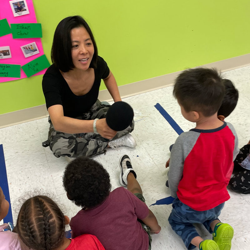 Teacher and kids at circle time learning mandarin and english at a dual-language preschool