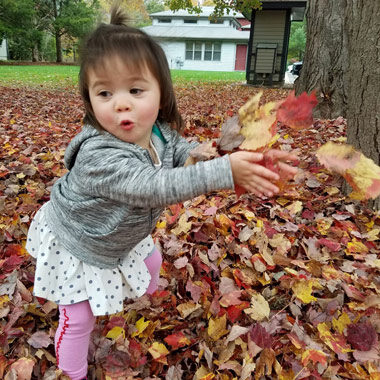 Toddler playing in the fall leaves